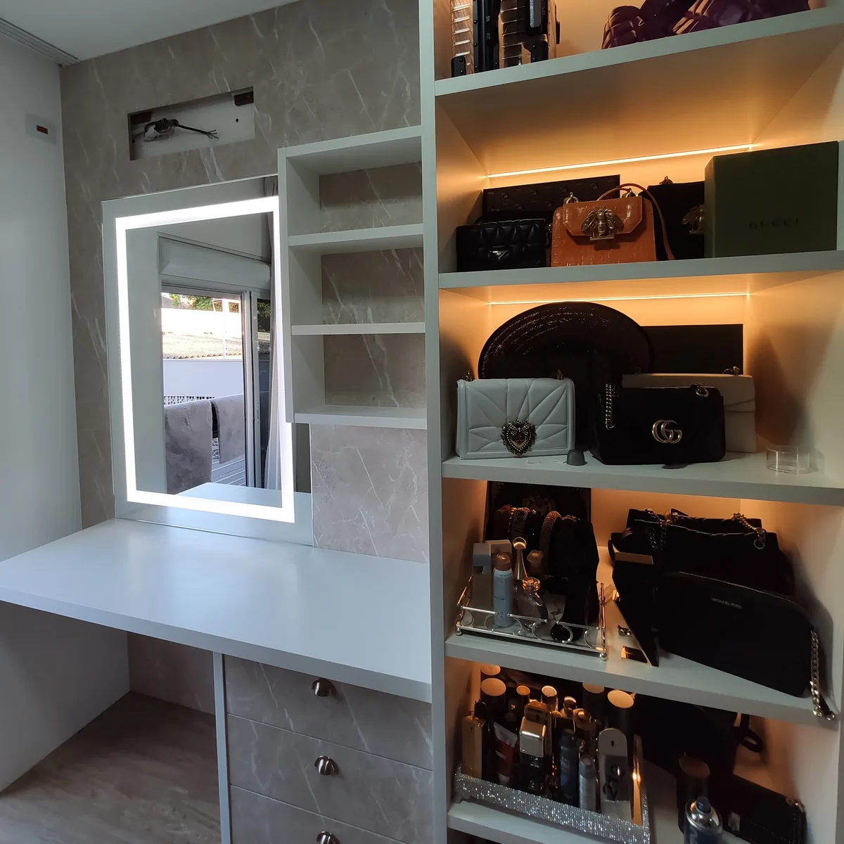 Closet com nichos iluminados para bolsas, penteadeira e espelho