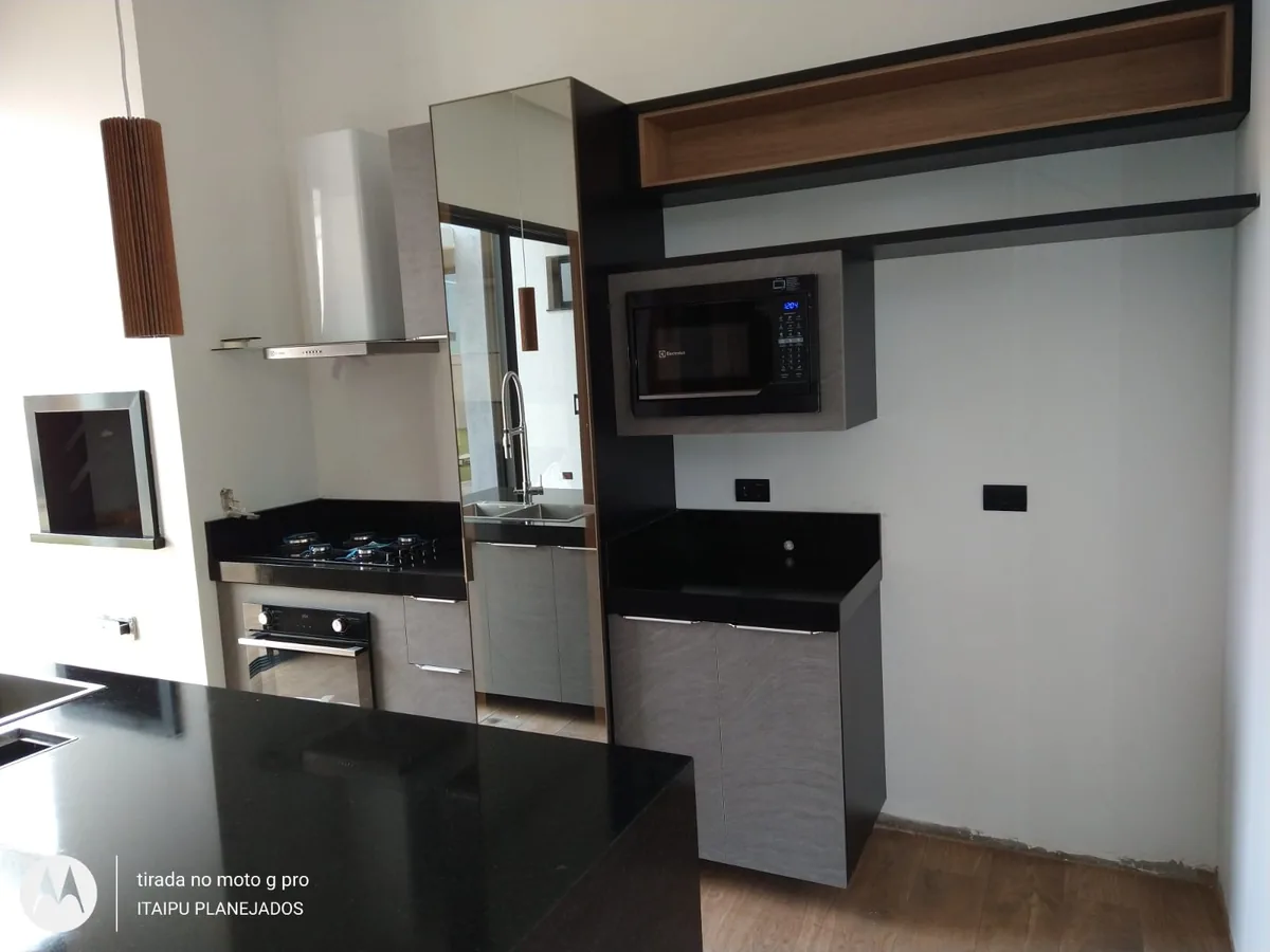 Cozinha planejada com armários cinza, nichos amadeirados e bancada preta