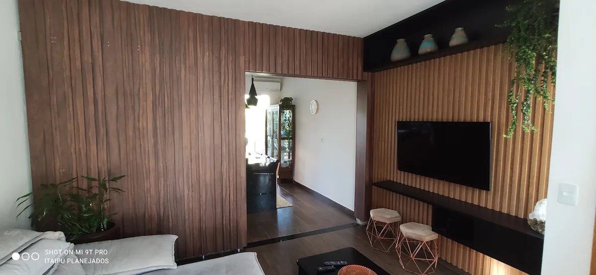 Sala com painéis ripados de madeira conectando o estar e a sala de jantar